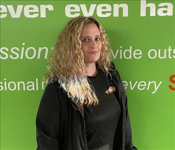 Female employee Trisha Burnette standing in front of a green wall with the SERVPRO logo