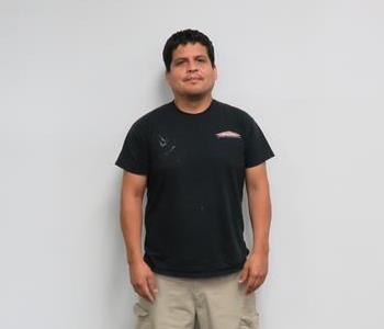 Male employee Chris Moldanado standing in front of a muted wall.
